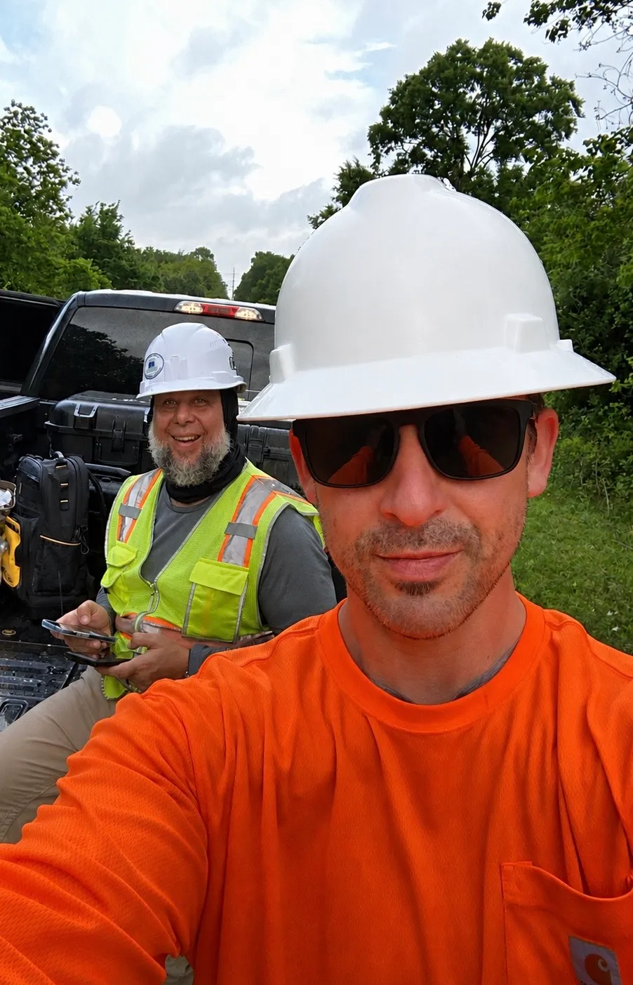 Two Axis crew members in hard hats and high-visibility gear at the truck between flights, field cases open on the tailgate.