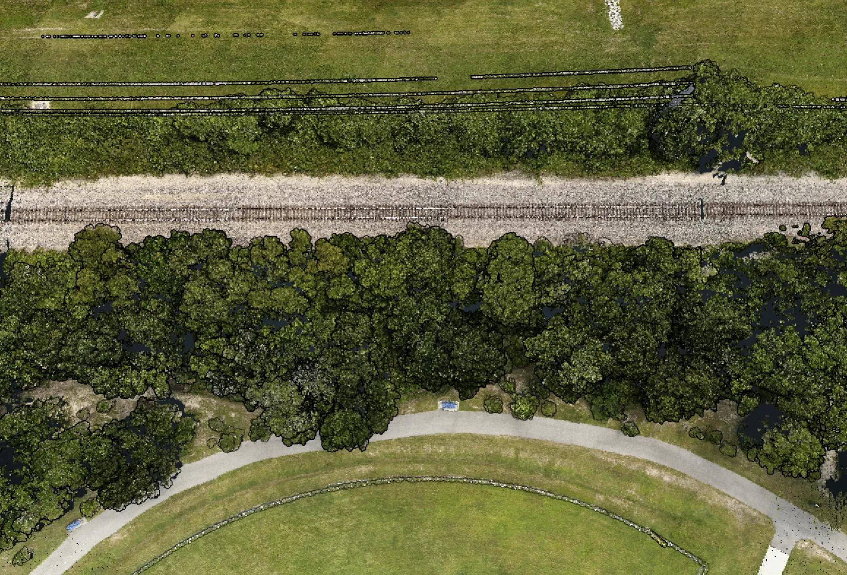 RGB-colorized point cloud of the elevated railroad embankment: track and ballast running between tree cover with the adjacent right-of-way.